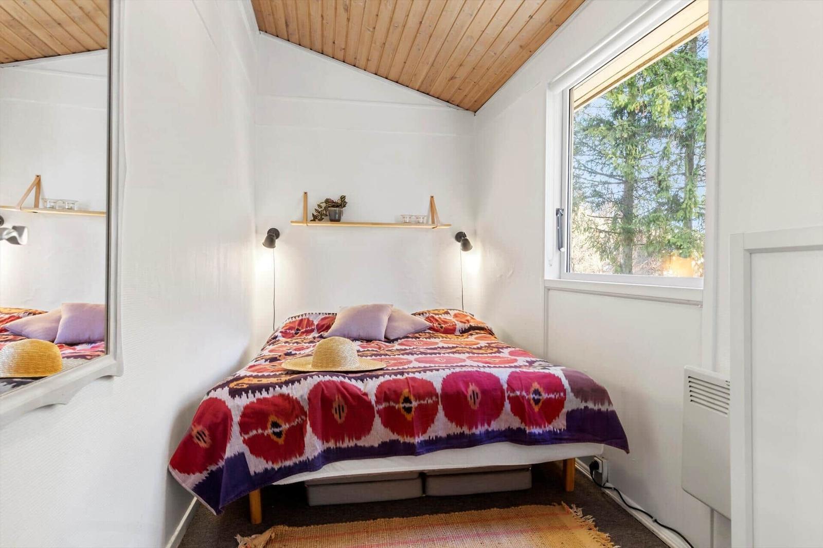 Bedroom with bed, window, and mirror on the wall.
