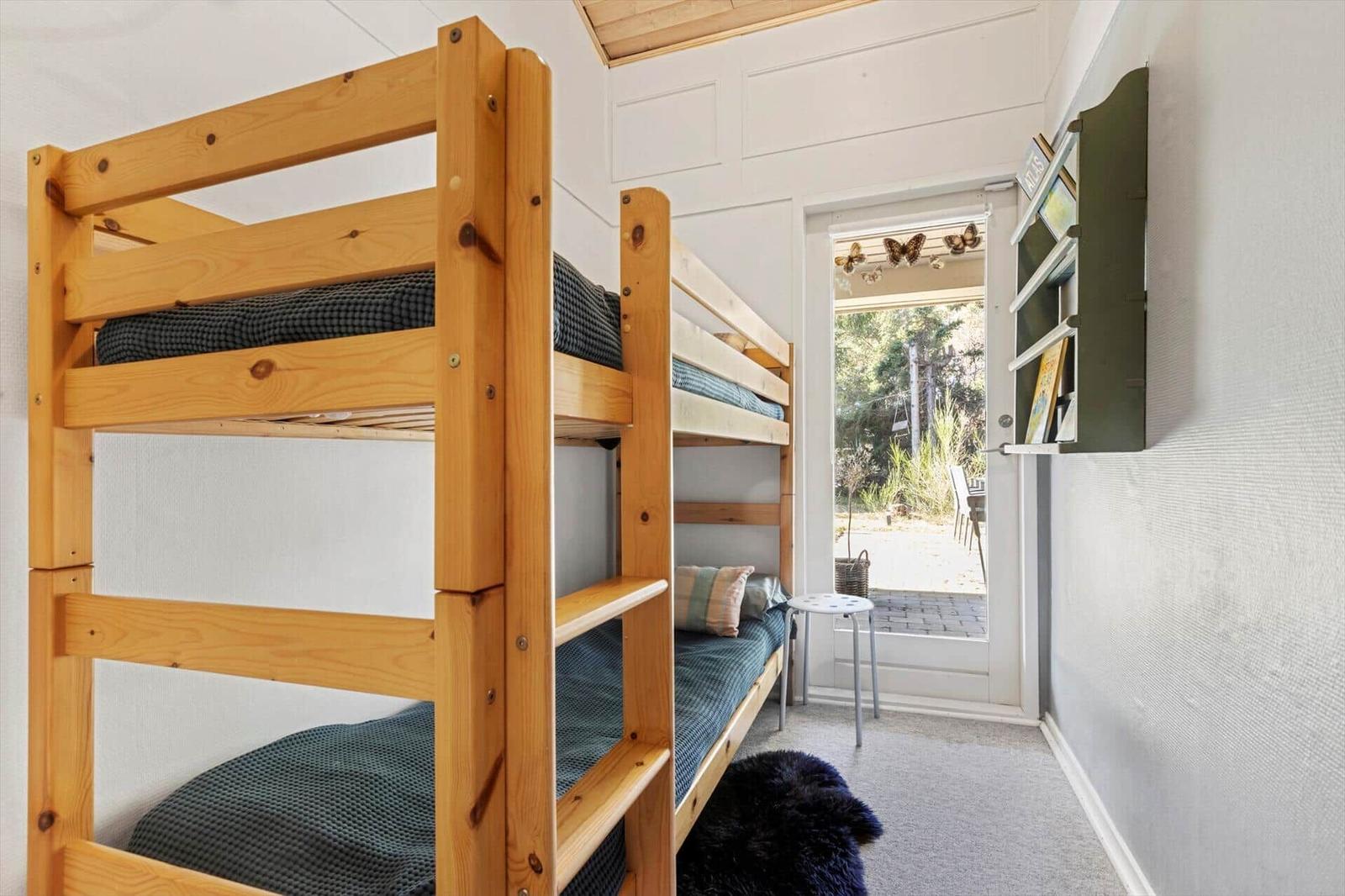 Room with wooden bunk bed and view of terrace.