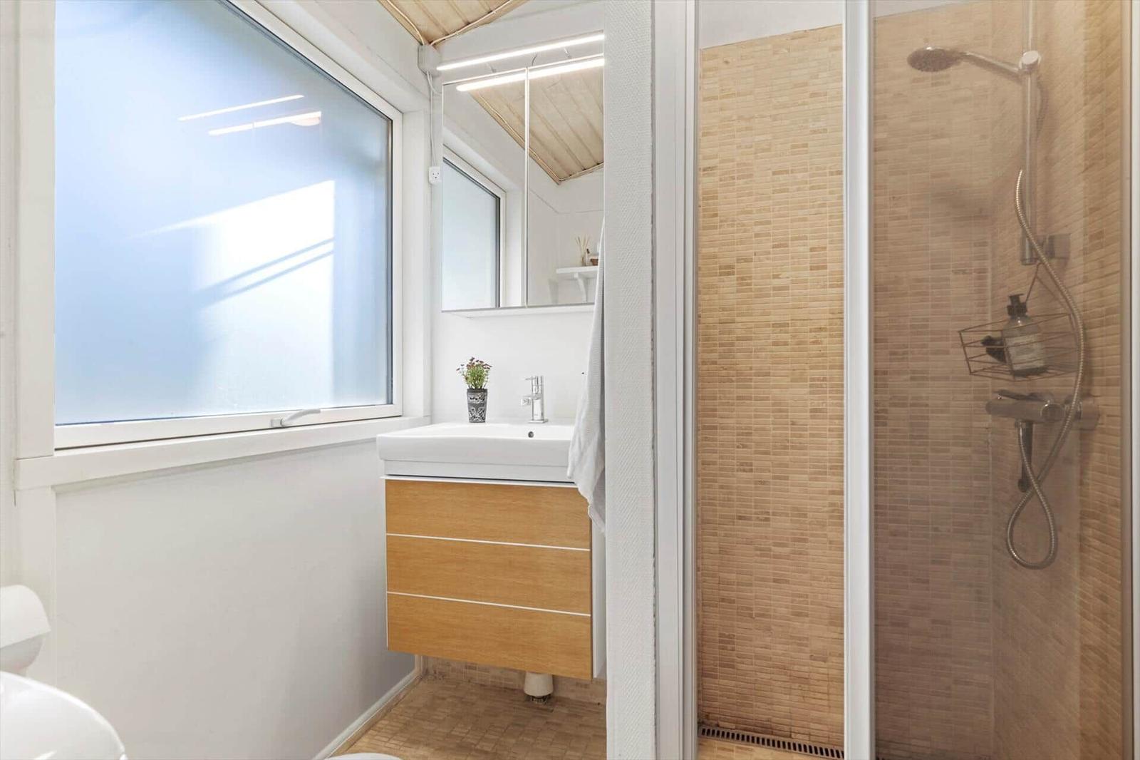 Bathroom with shower, sink, and window