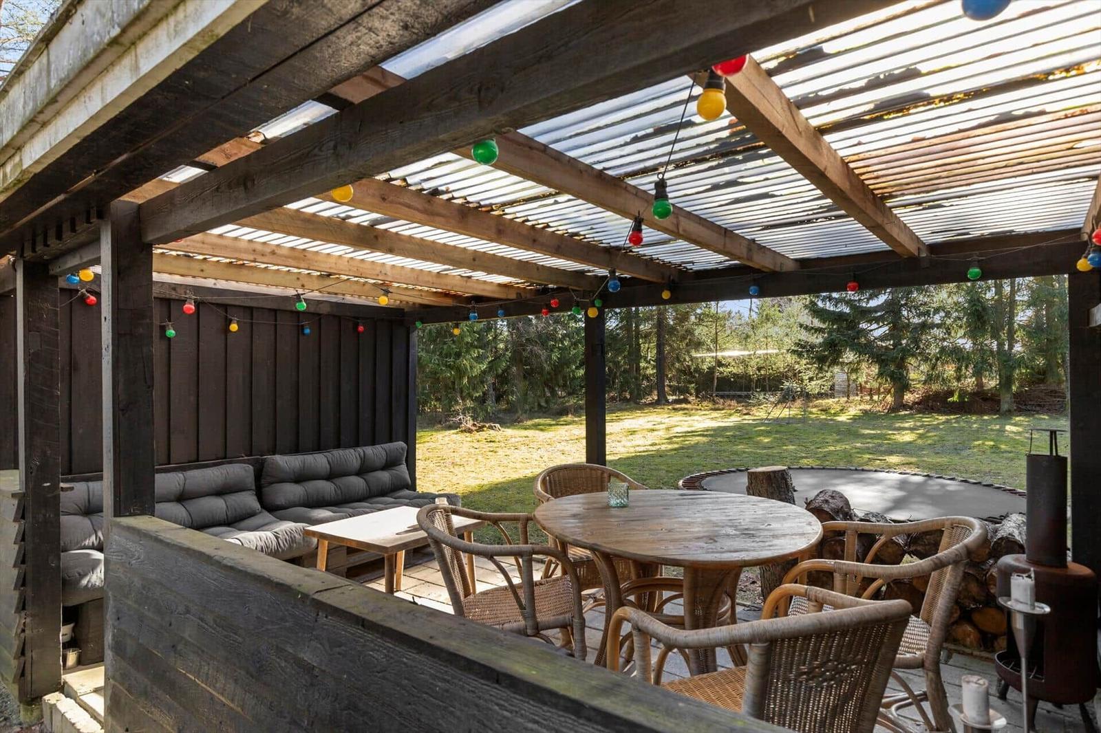 Patio with seating, table, chairs, and string lights under roof.