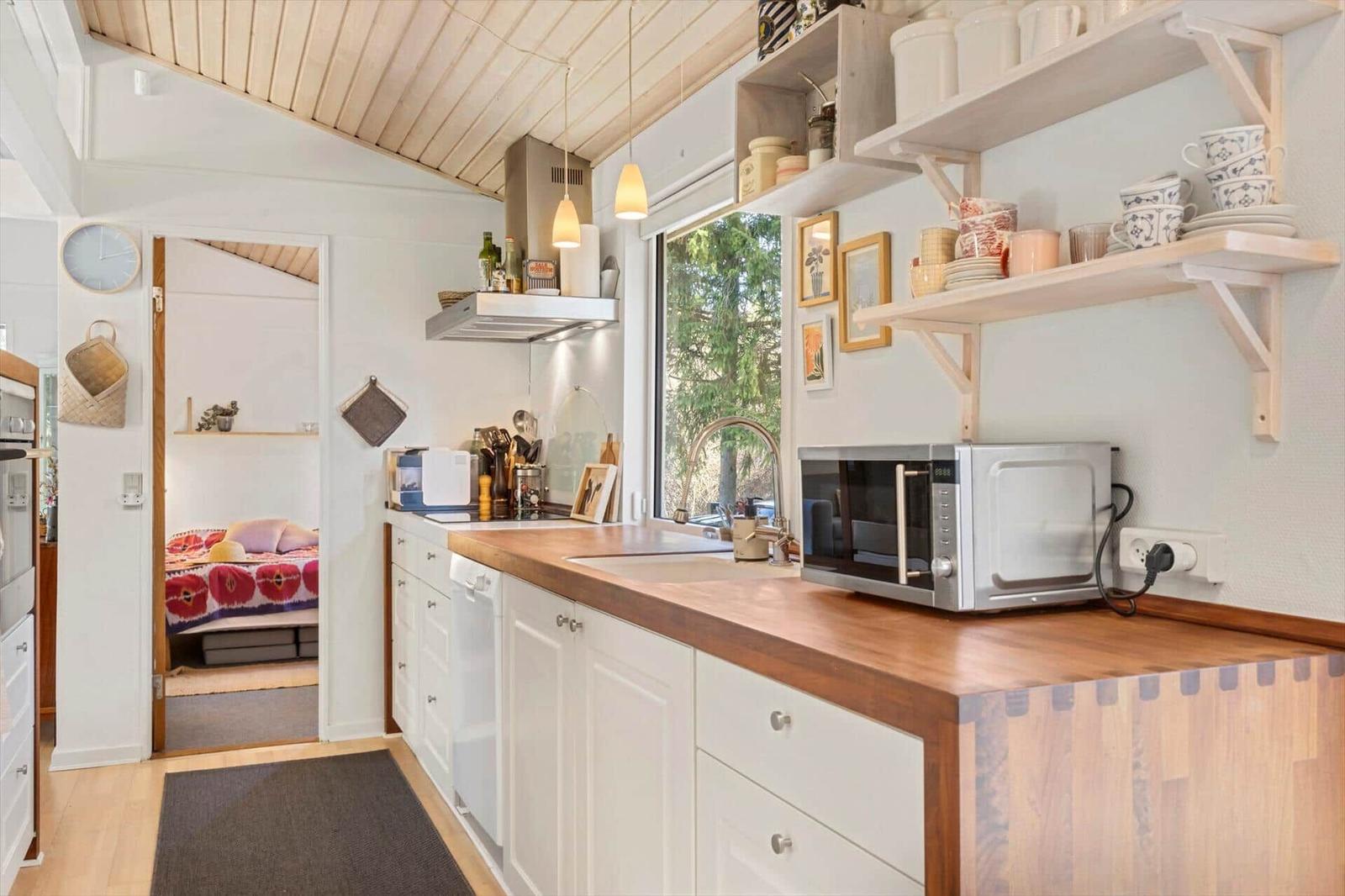 Kitchen with wooden countertop, microwave, and view into bedroom