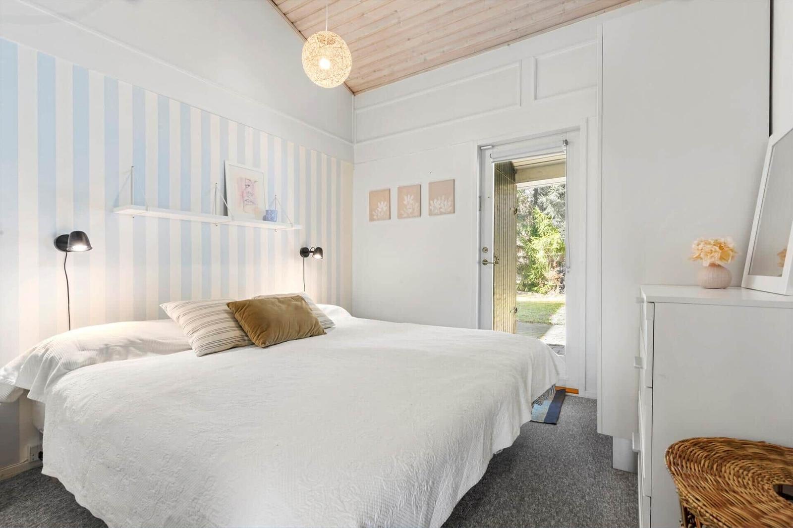 Bedroom with bed, striped wall, and door to garden.