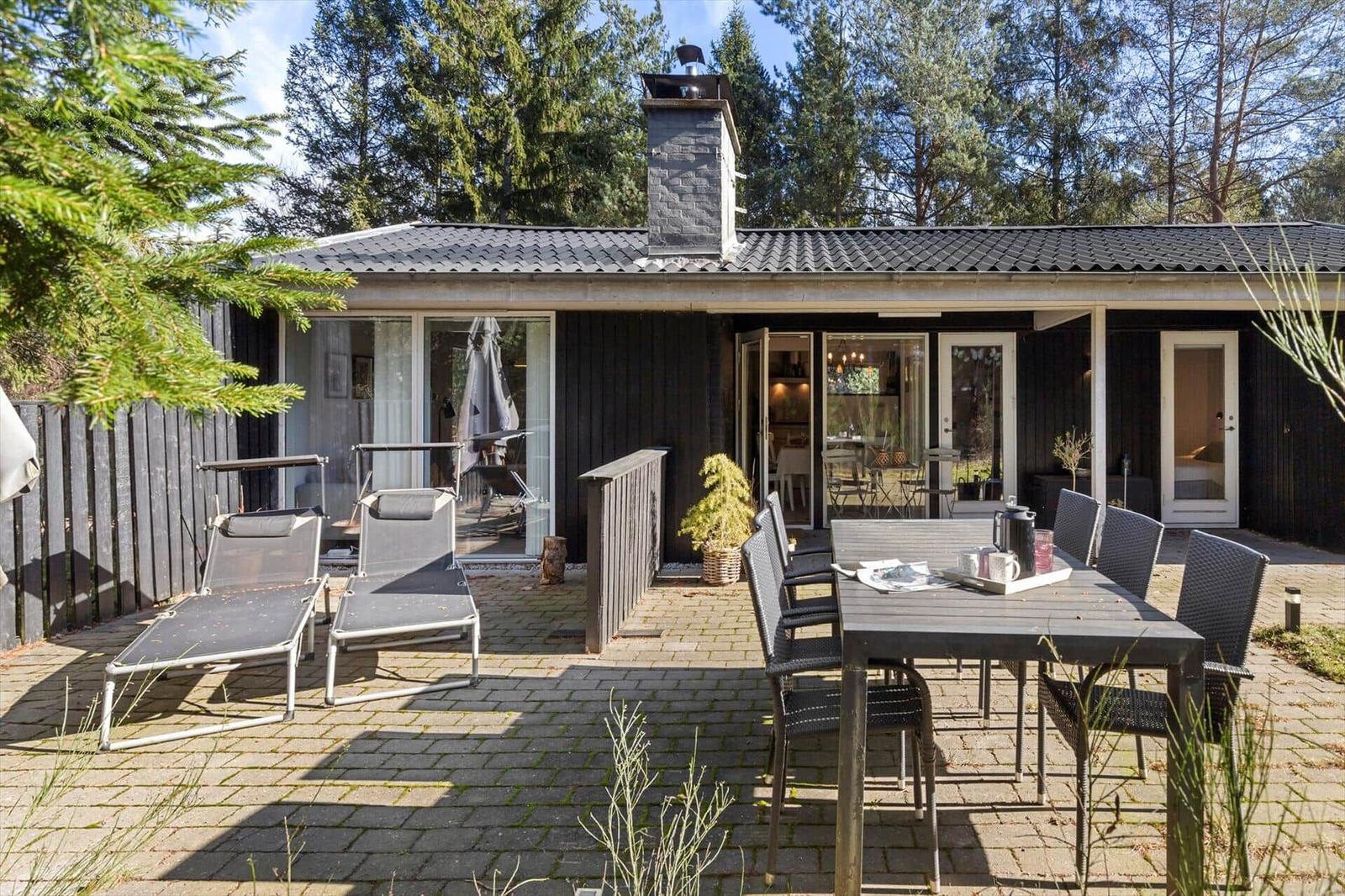 House with terrace, garden furniture, and grill area in the woods
