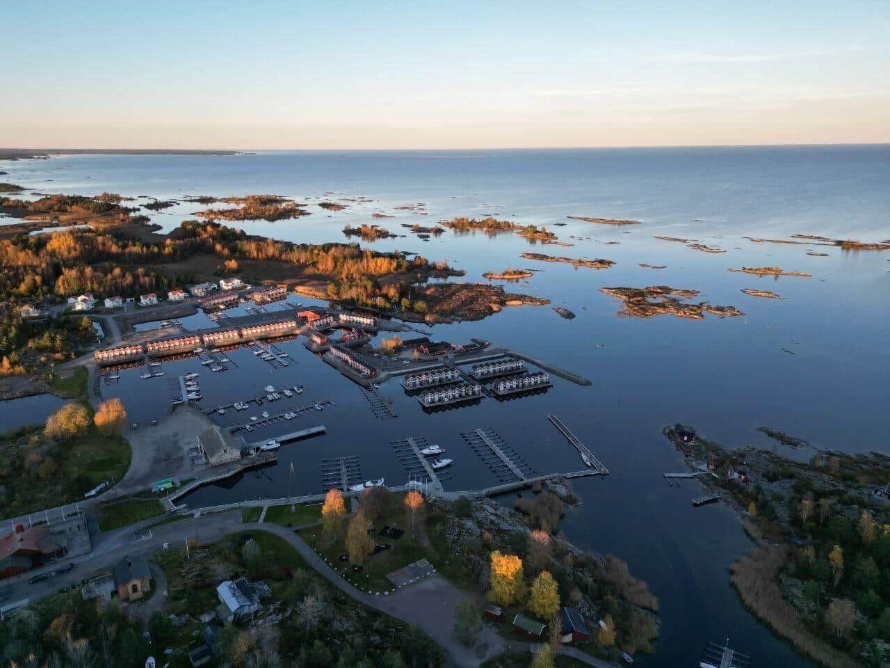 Aerial view of a coastal village with marina, boats, and surrounding islands.