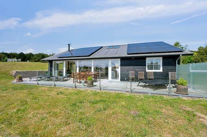 Moderne Villa mit Solaranlage und großem Außenbereich mit Sitzgelegenheiten.