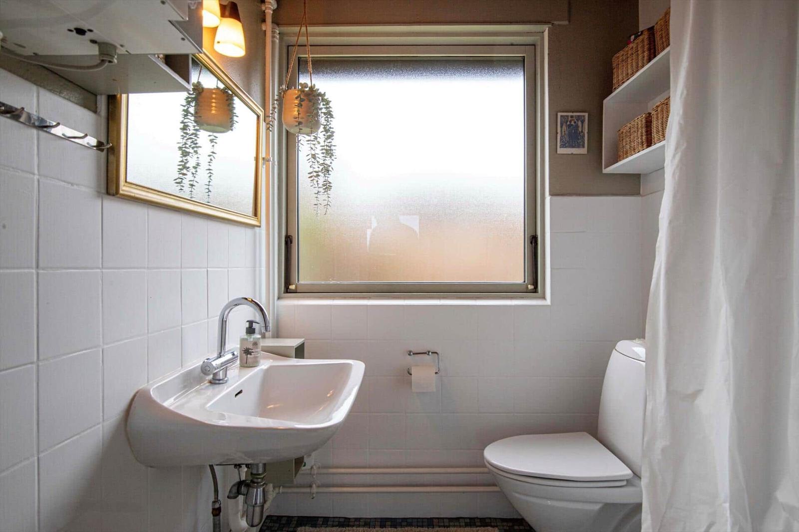 Badezimmer mit Waschbecken, Toilette und Fenster mit Milchglas.