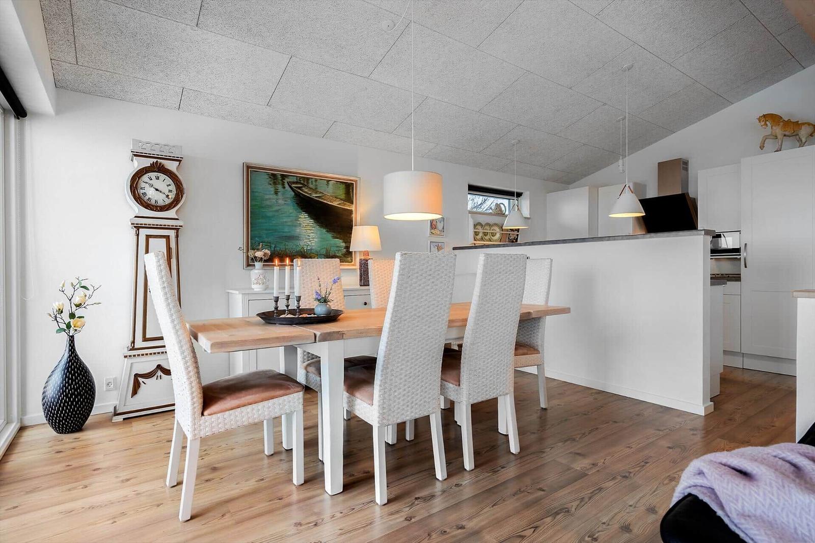 Essbereich mit Tisch, Stühlen und Uhr an der Wand.
