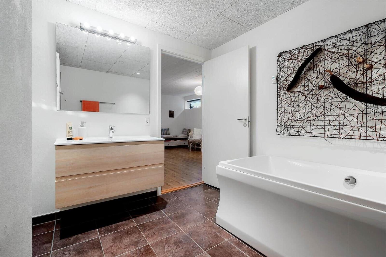 Badezimmer mit Badewanne, Waschbecken und Wandkunst.