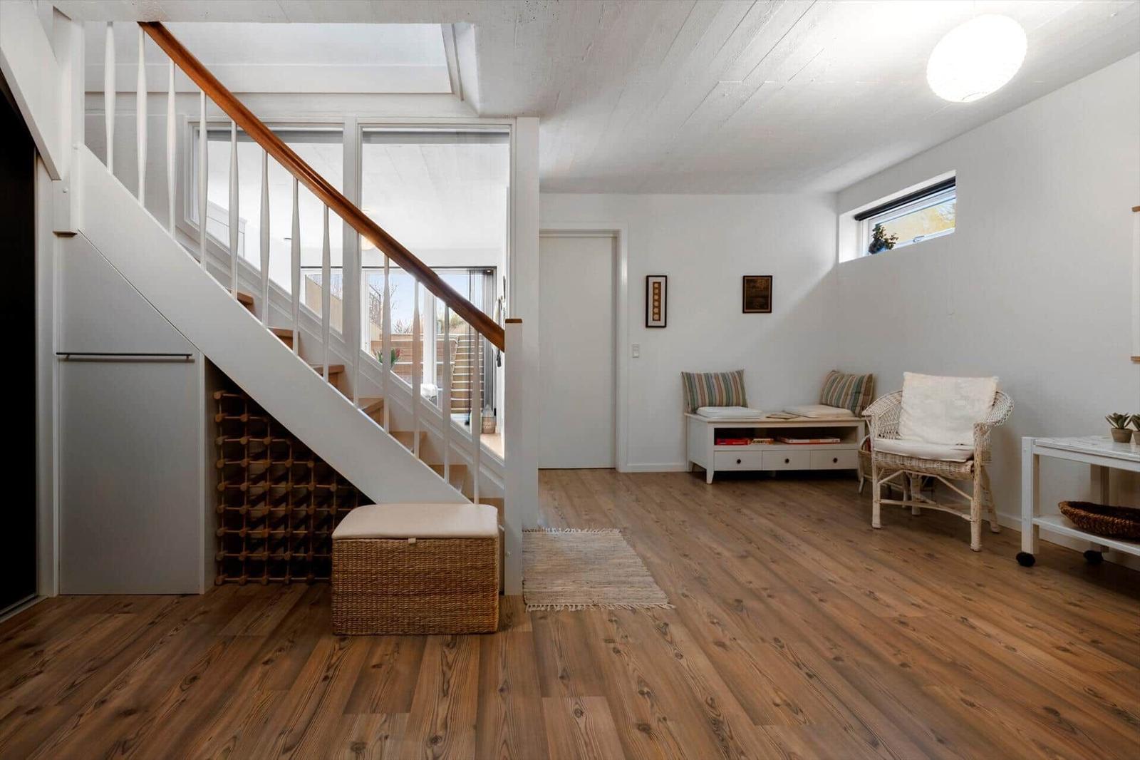 Eingangsbereich mit Treppe, Sitzgelegenheit und Holzboden.