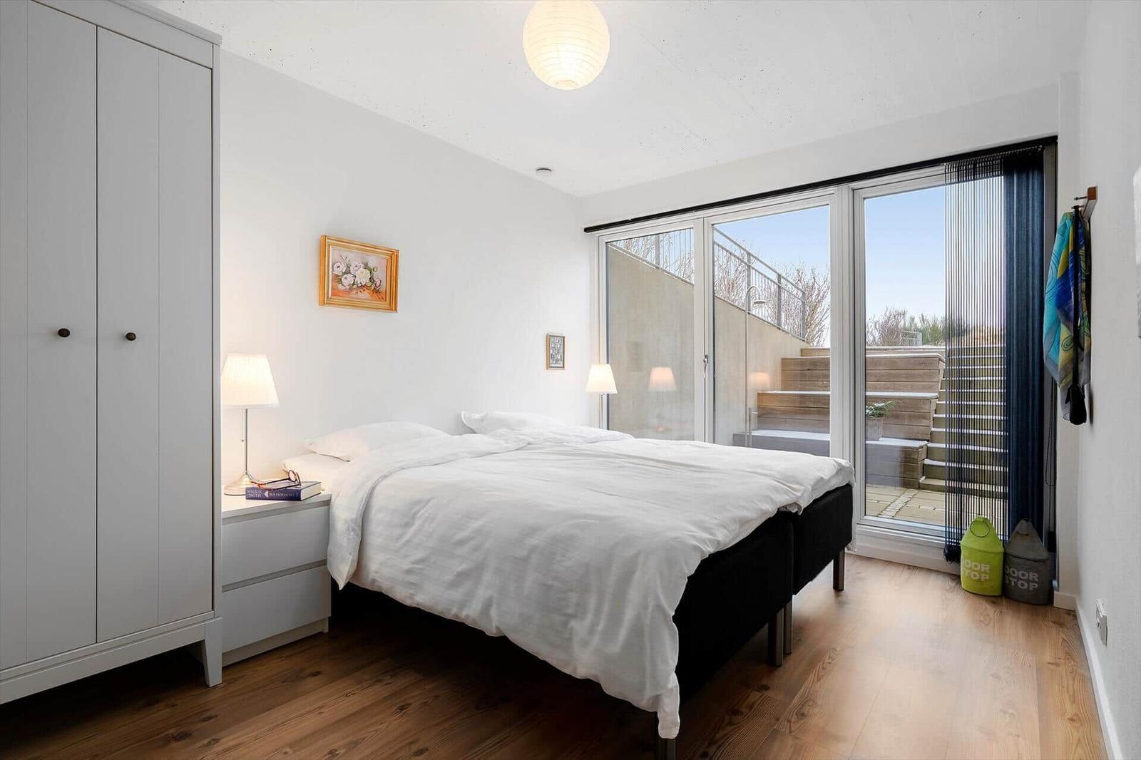 Schlafzimmer mit Doppelbett, Kleiderschrank und Blick auf Terrasse