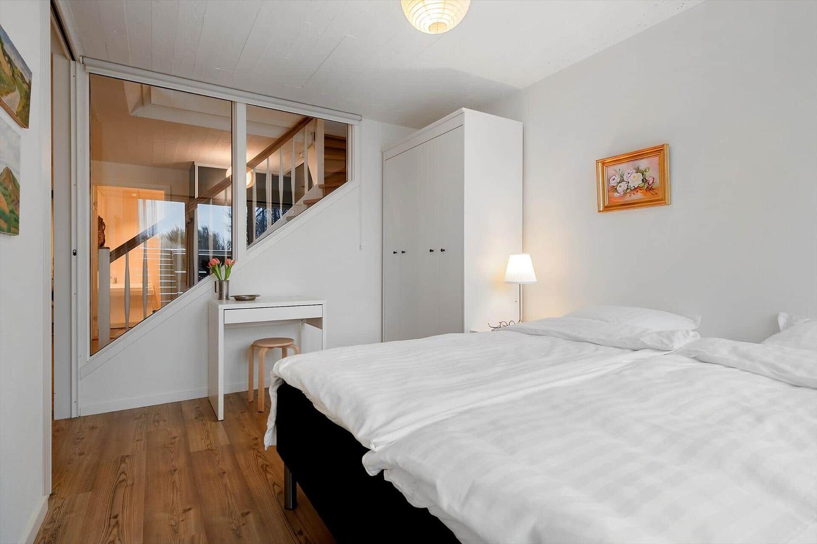 Schlafzimmer mit Bett, Schrank und Spiegelwand. Holzboden und Wandbild.