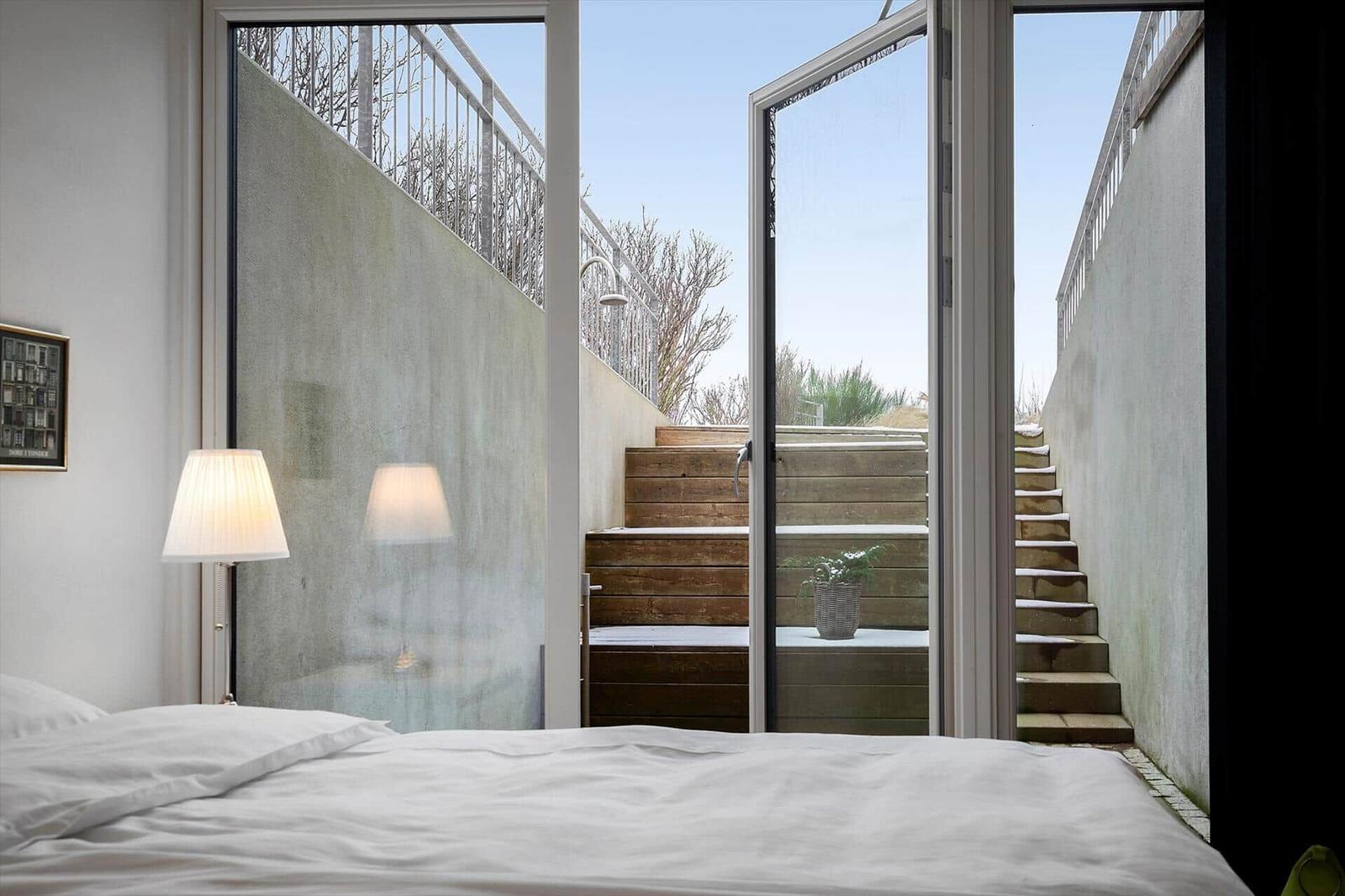 Schlafzimmer mit Blick auf Holztreppe und Außenbereich.