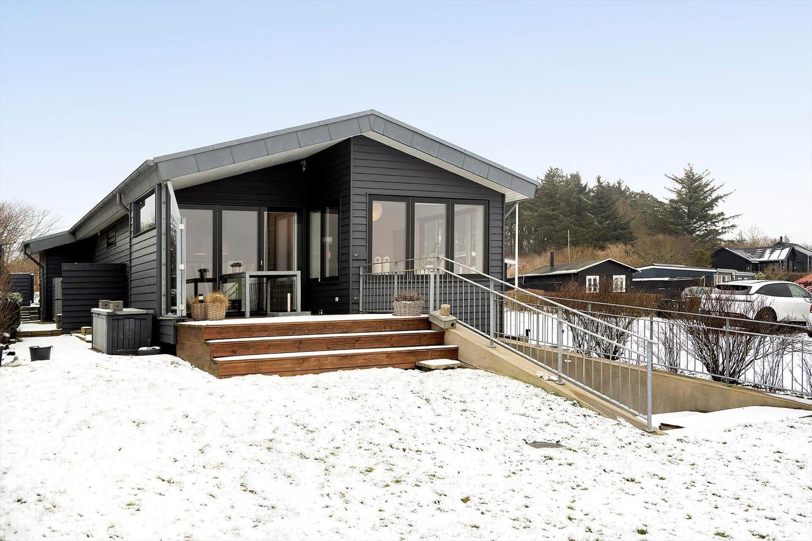 Moderne Villa mit Holzterrasse und Schneebedecktem Grundstück.