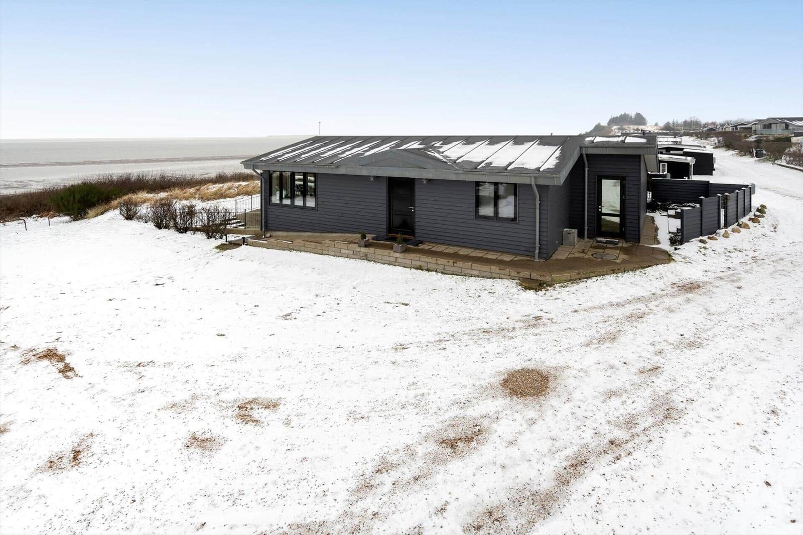 Modernes Haus mit Schnee, Blick auf Meer und Himmel.
