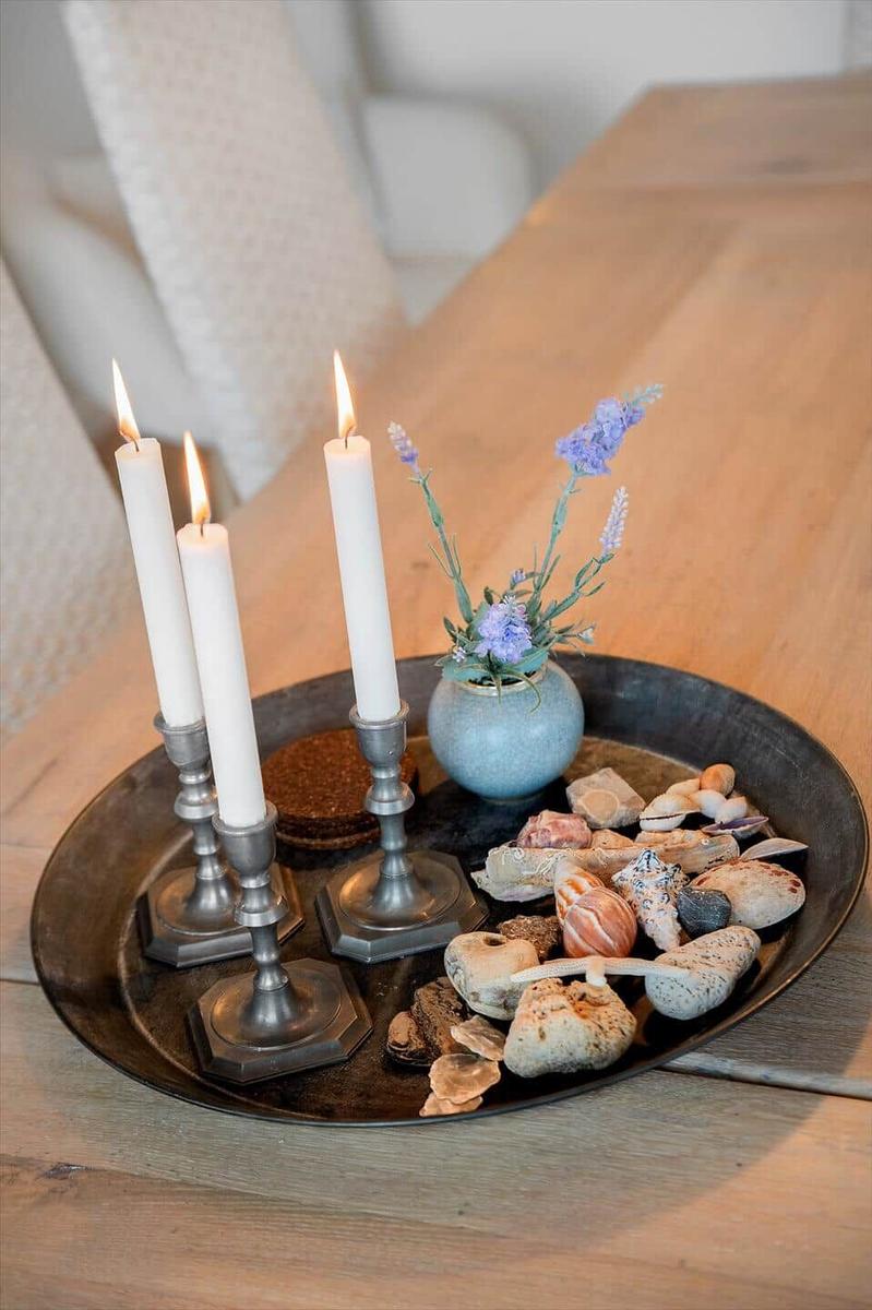 Drei brennende Kerzen, Lavendel und Muscheln auf einem Metalltablett.