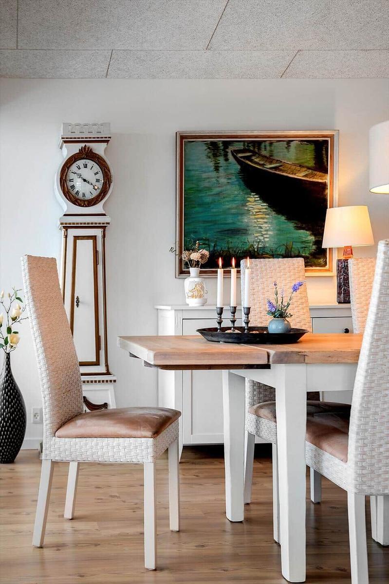 Esszimmer mit Tisch, Stühlen, Wanduhr und Gemälde.
