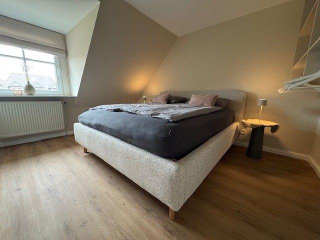 Schlafzimmer mit Dachschräge, Bett, Nachttisch und Fenster.
