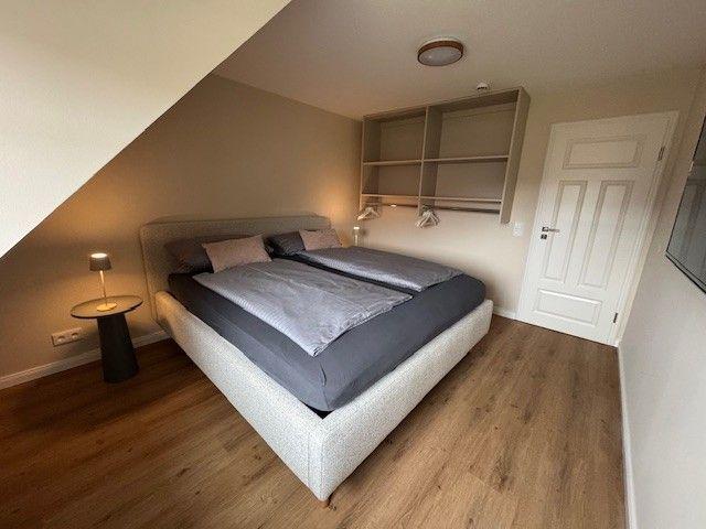 Schlafzimmer mit Doppelbett, Schrank und Holzboden.