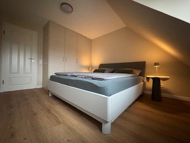 Schlafzimmer mit Dachschräge, weißem Bett und Holzboden