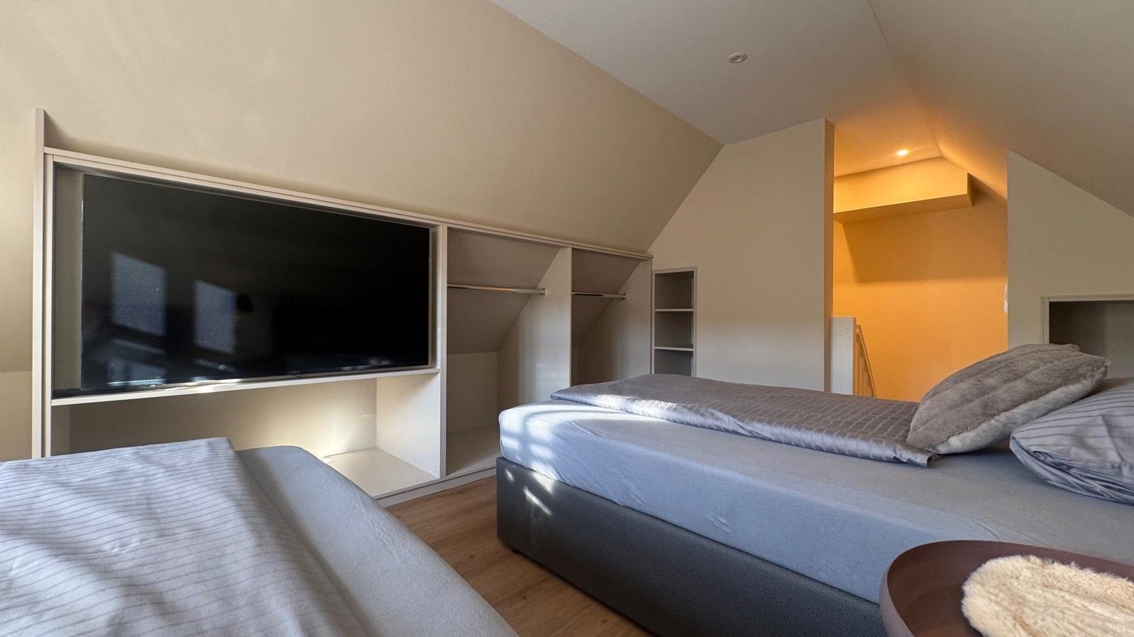 Schlafzimmer mit Bett, Kleiderschrank und Fernseher.