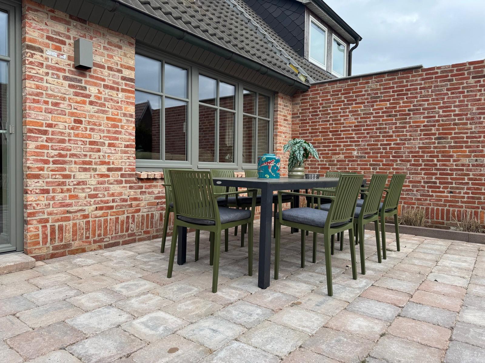 Terrasse mit Tisch und Stühlen vor Backsteinhaus