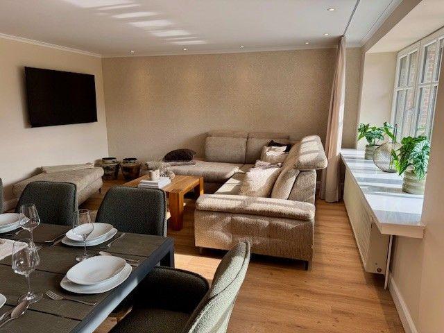 Wohn- und Essbereich mit Sofa, Esstisch und TV.