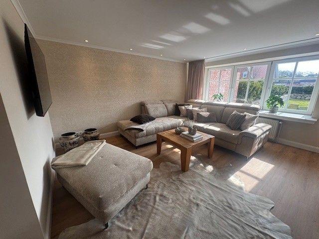 Wohnzimmer mit Sofa, Couchtisch und Fernseher an der Wand.