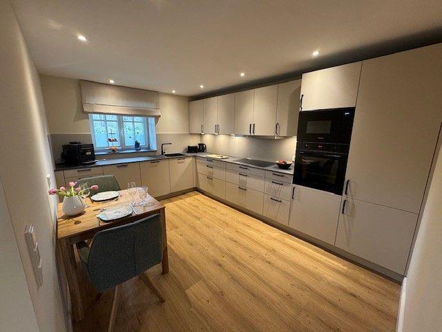 Küche mit Essbereich, Holzboden und modernen Schränken.