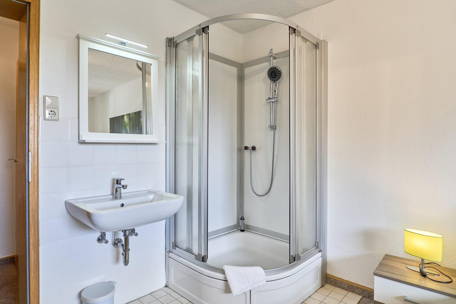 Badezimmer mit Duschkabine, Waschbecken und Spiegel.