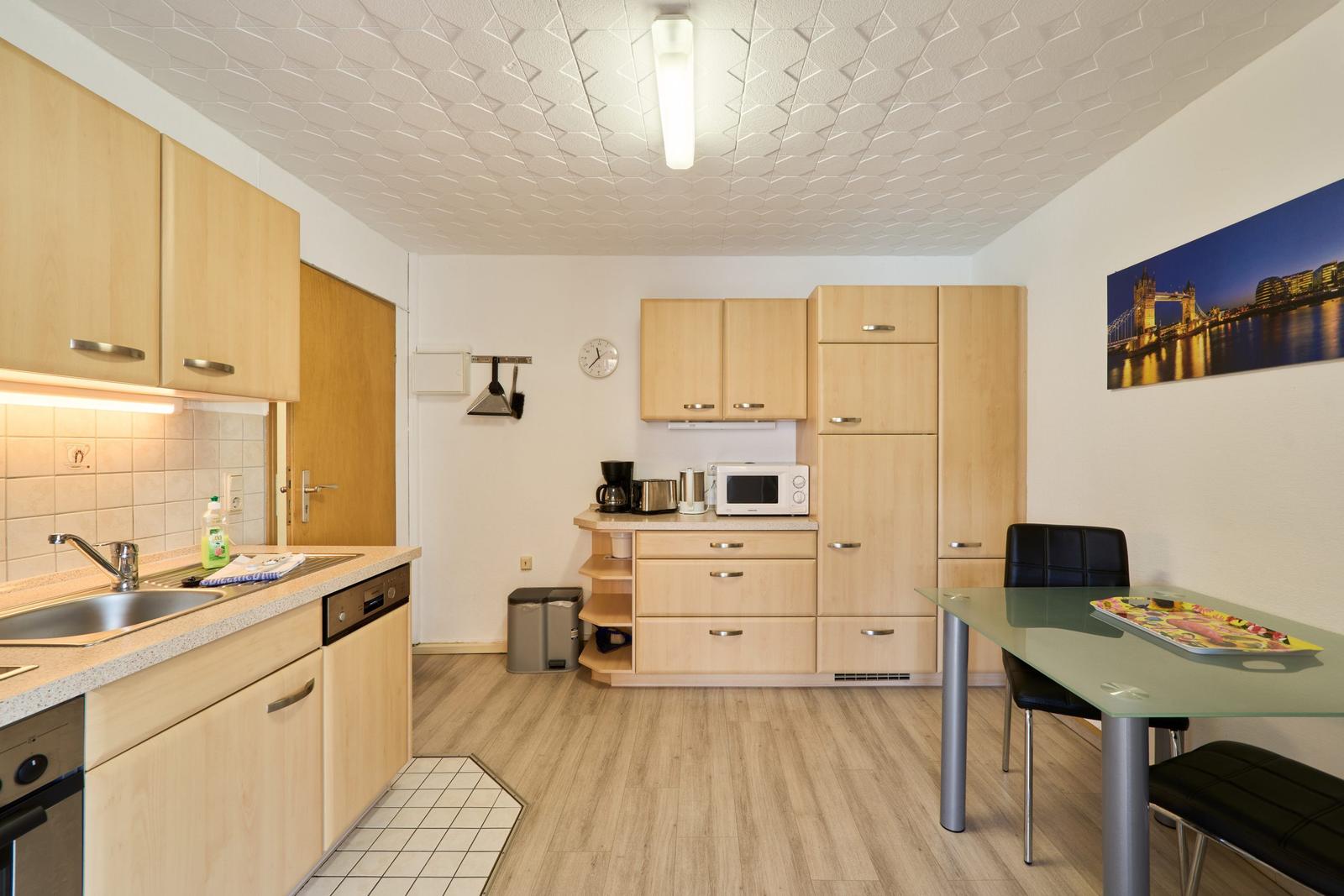 Küche mit Essbereich, Holzmöbel und Glasplatte. Wandbild Tower Bridge.