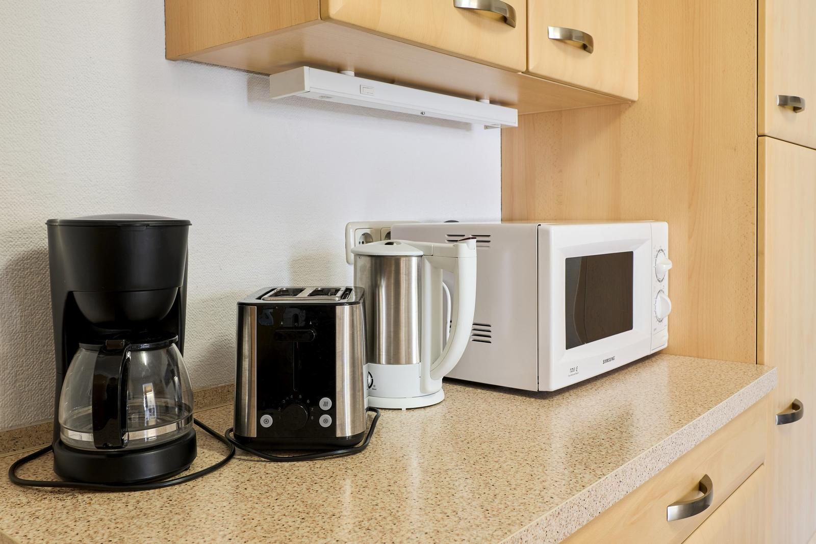 Küchenzeile mit Kaffeemaschine, Toaster, Kaffeemaschine und Mikrowelle.