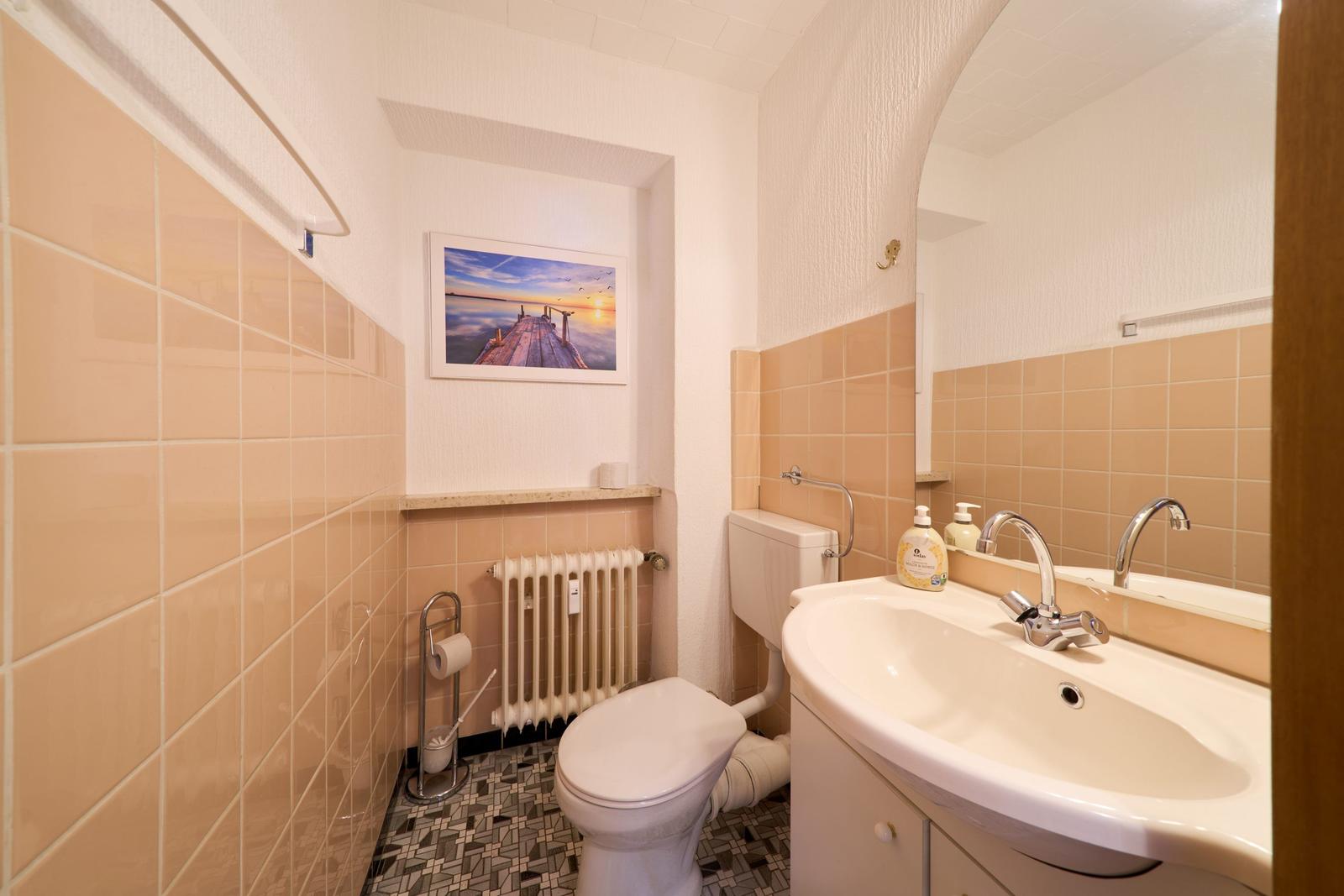 Badezimmer mit Toilette, Waschbecken und Wandbild.