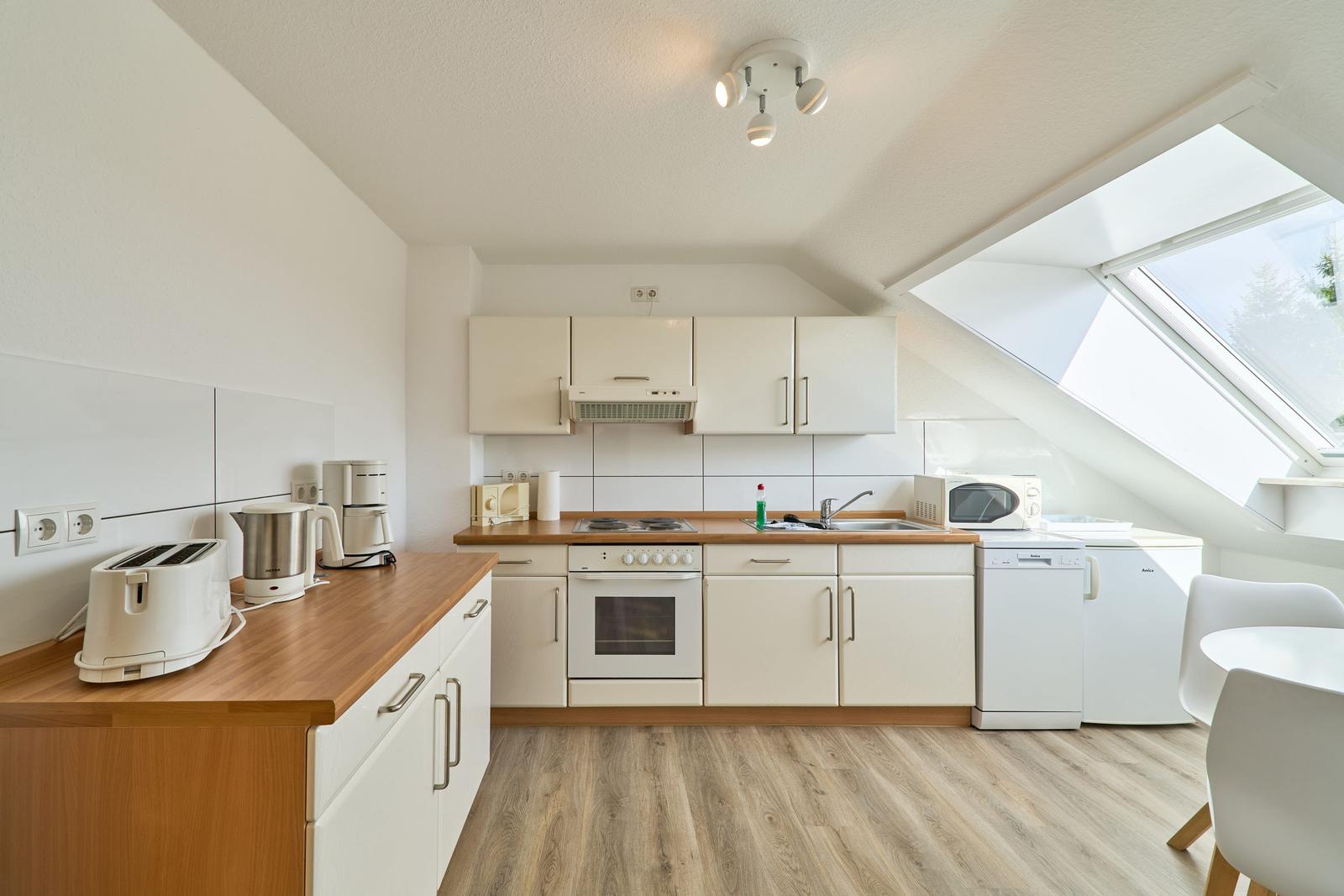 Küche mit Dunstabzug, Herd, Spüle und Fenster