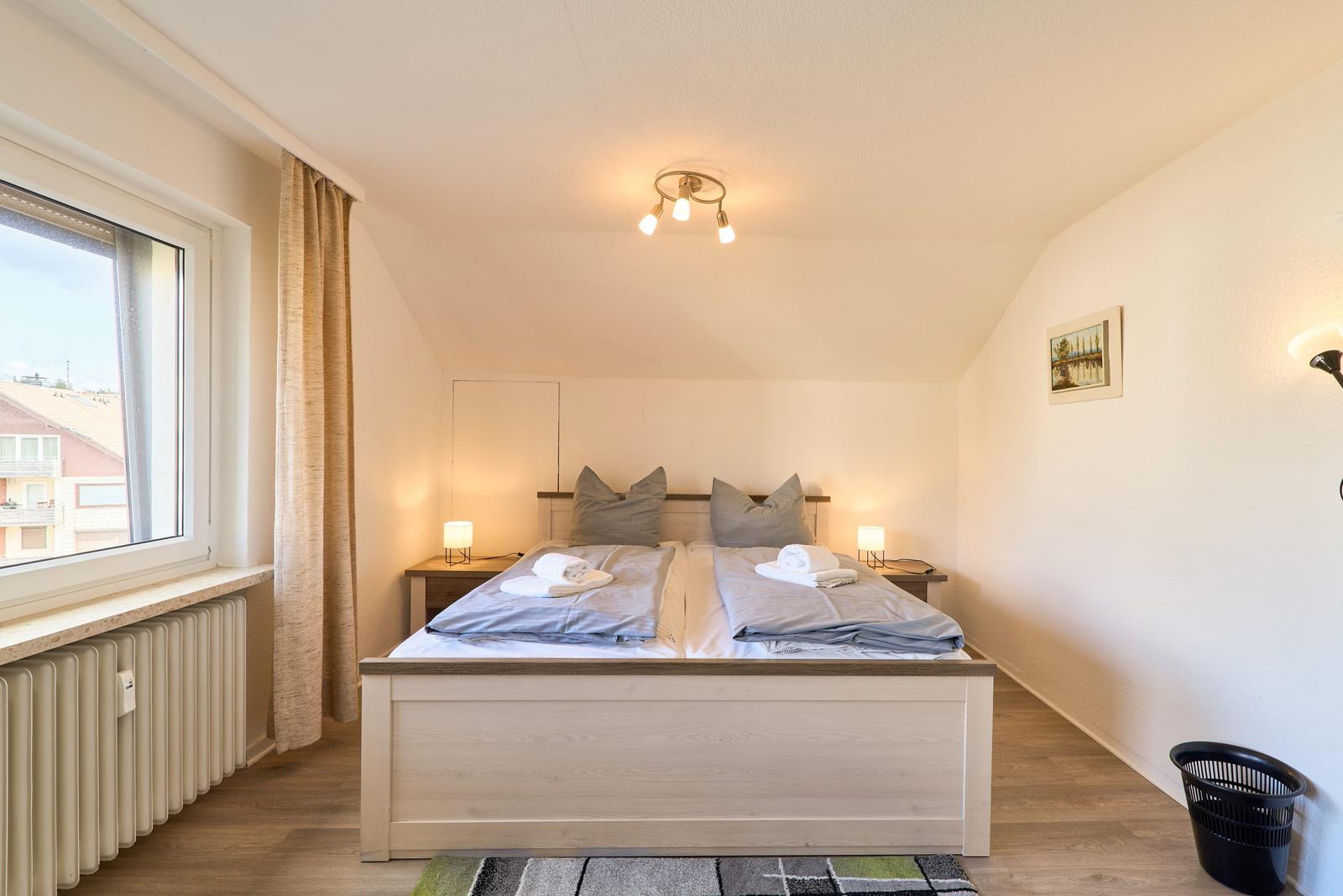 Schlafzimmer mit Doppelbett, Fenster und Nachttischen.