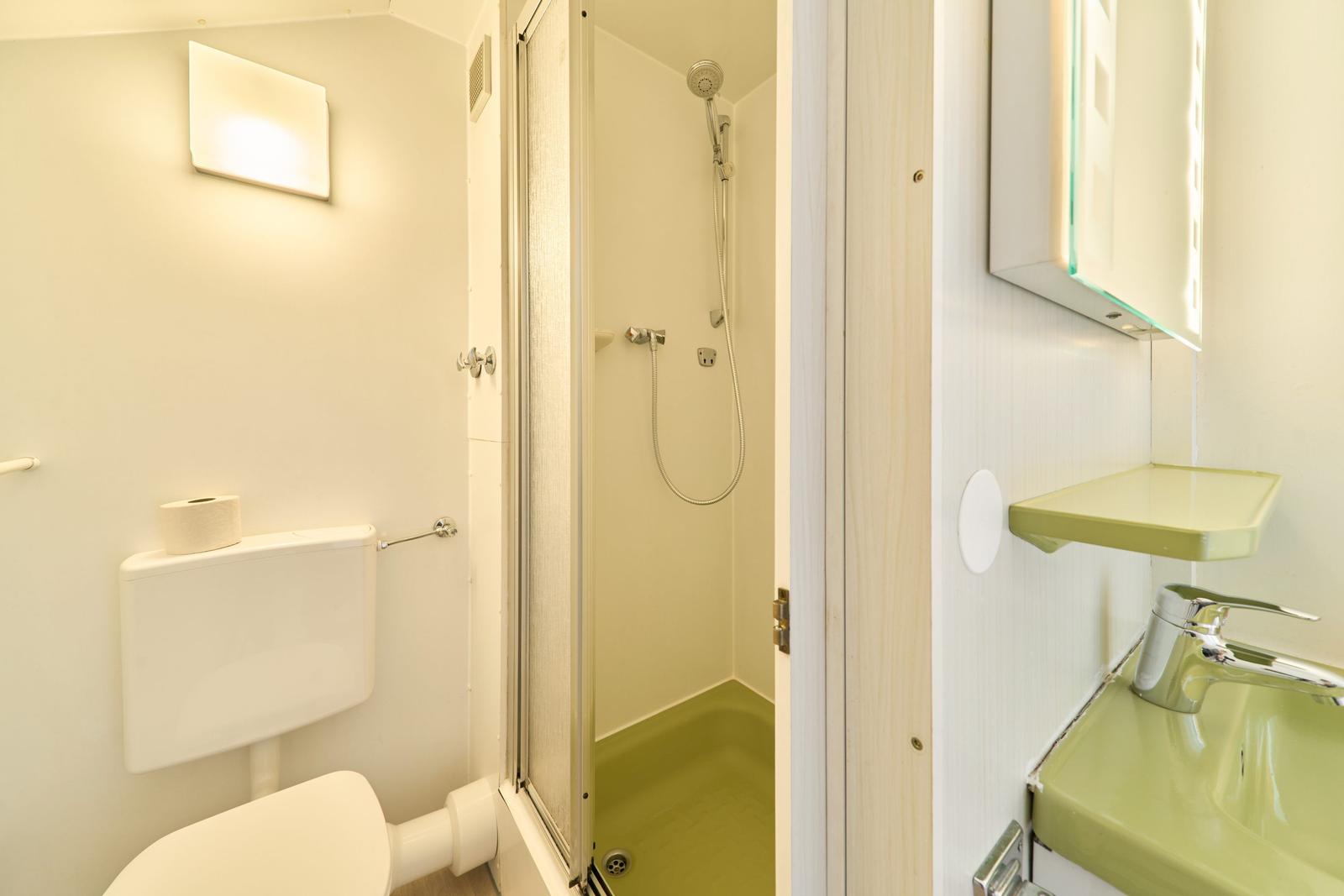 Badezimmer mit Dusche, Toilette und Waschbecken.