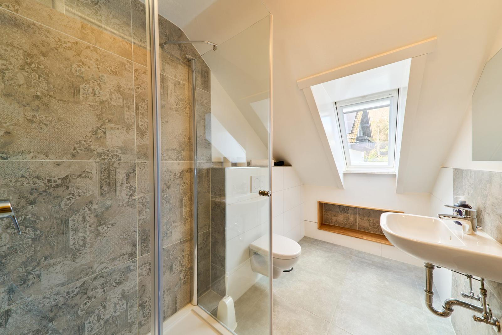 Badezimmer mit Dusche, Toilette und Waschbecken unter Dachschrägen
