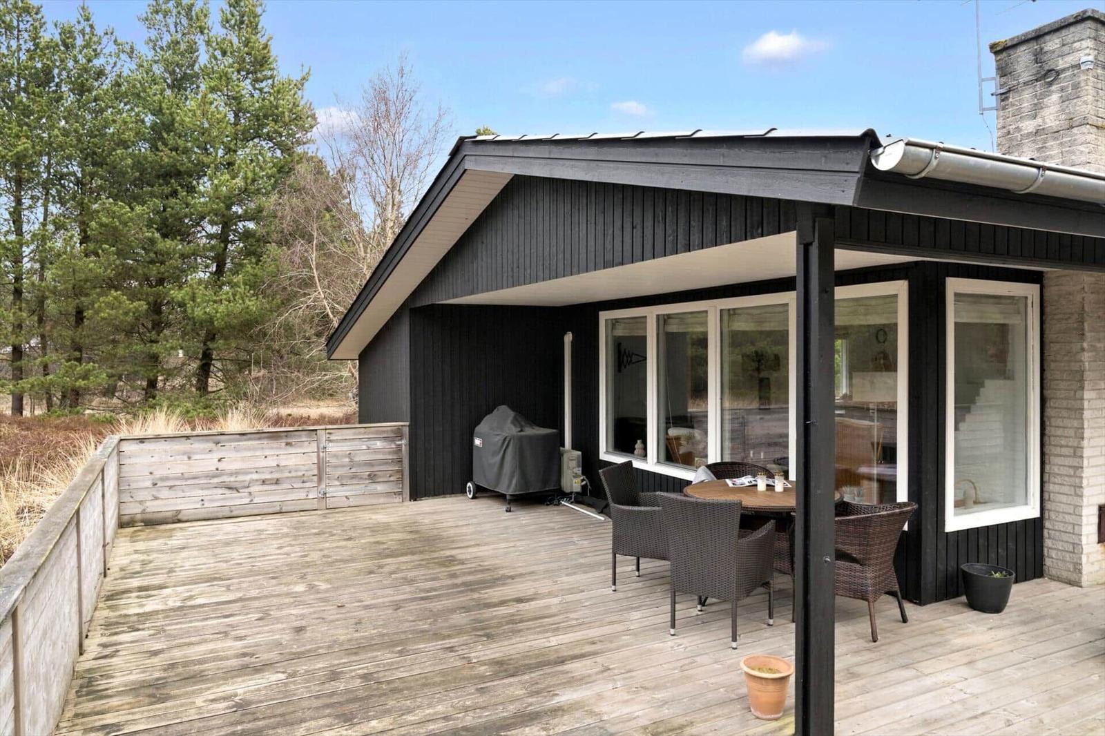 Terrasse mit Sitzgruppe, Grill und Blick in den Wald.