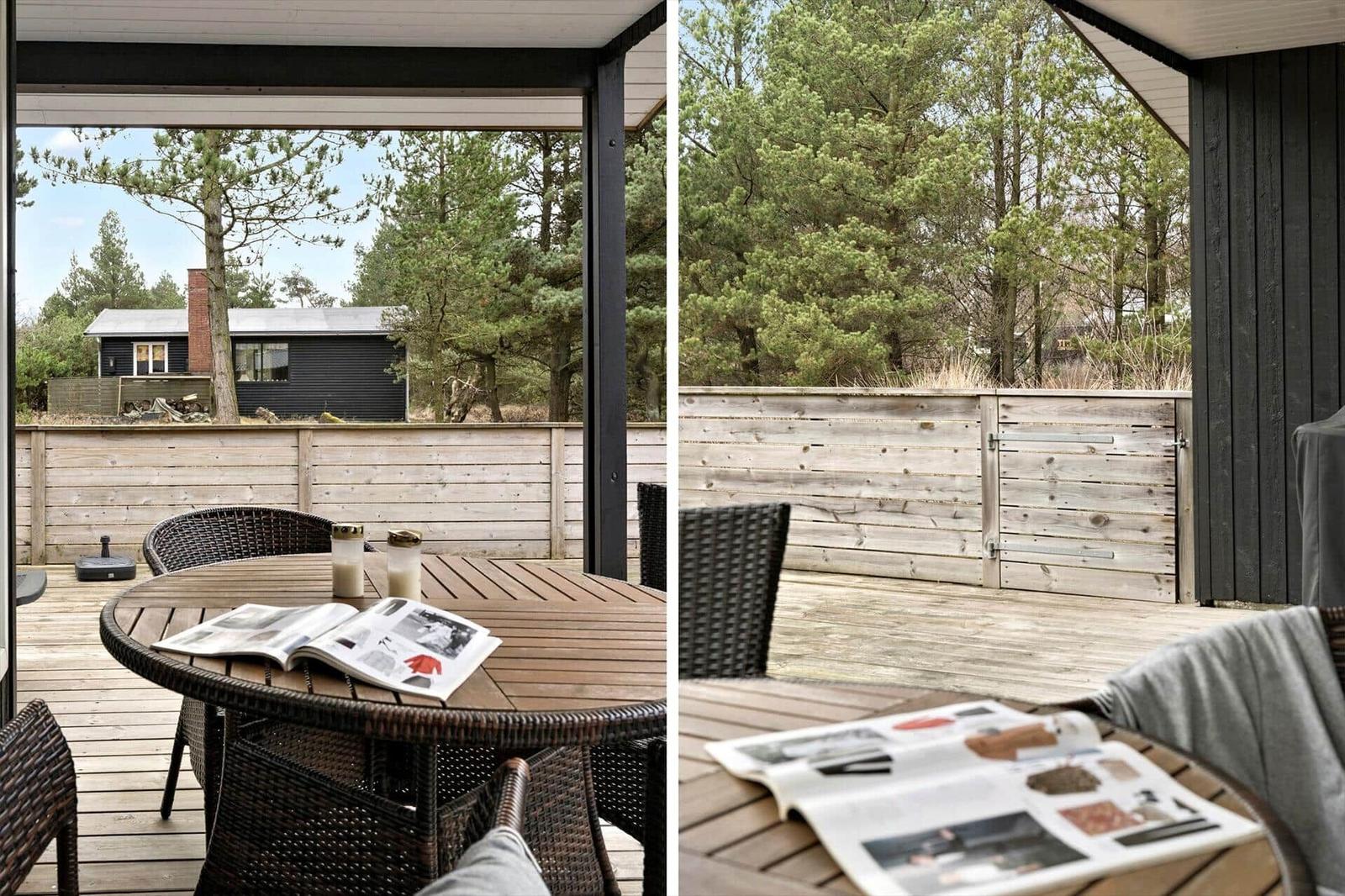 Terrasse mit Tisch und Stühlen, Blick auf Wald und Holzzaun.