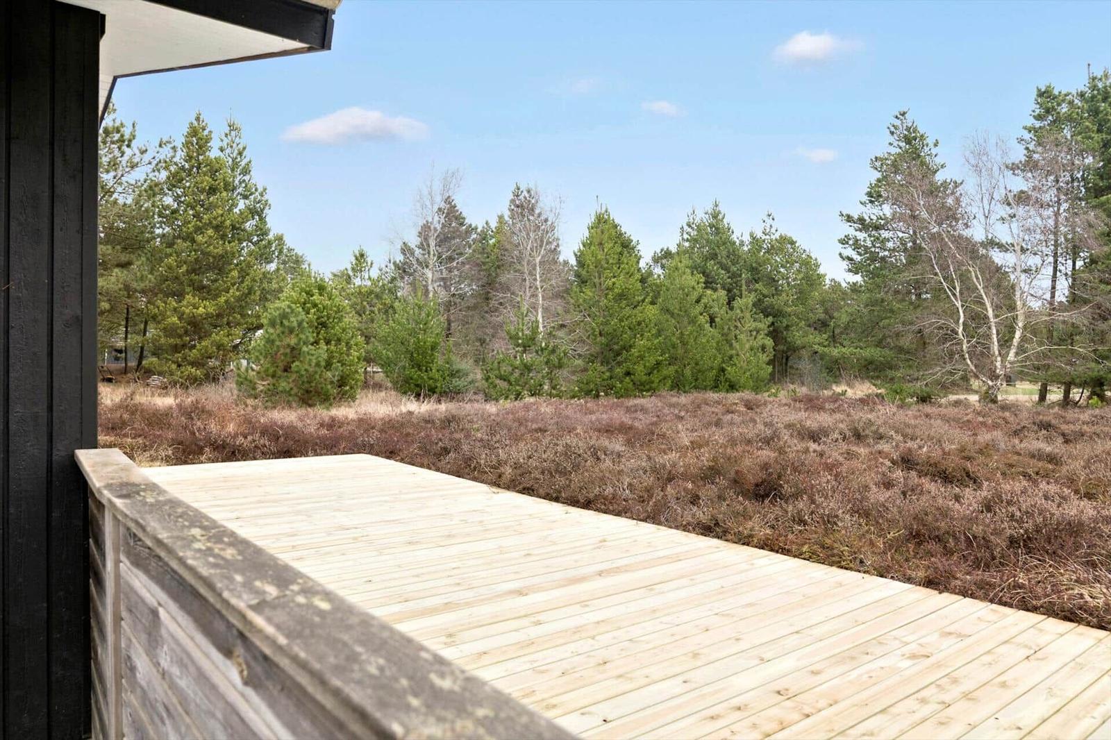 Holzterrasse mit Blick auf Wald und Heide.
