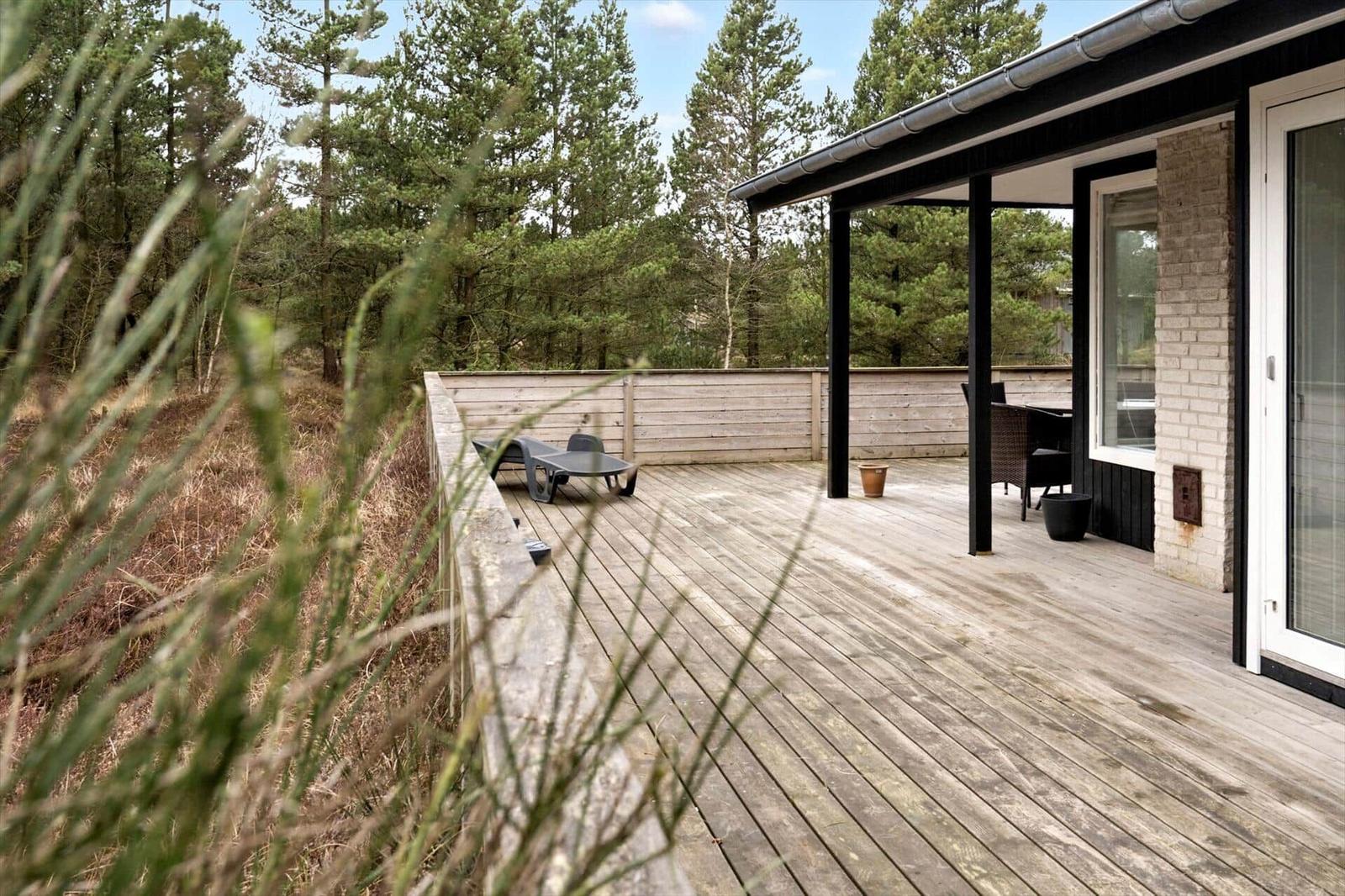 Holzterrasse mit Liegestuhl und Sitzgruppe im Wald