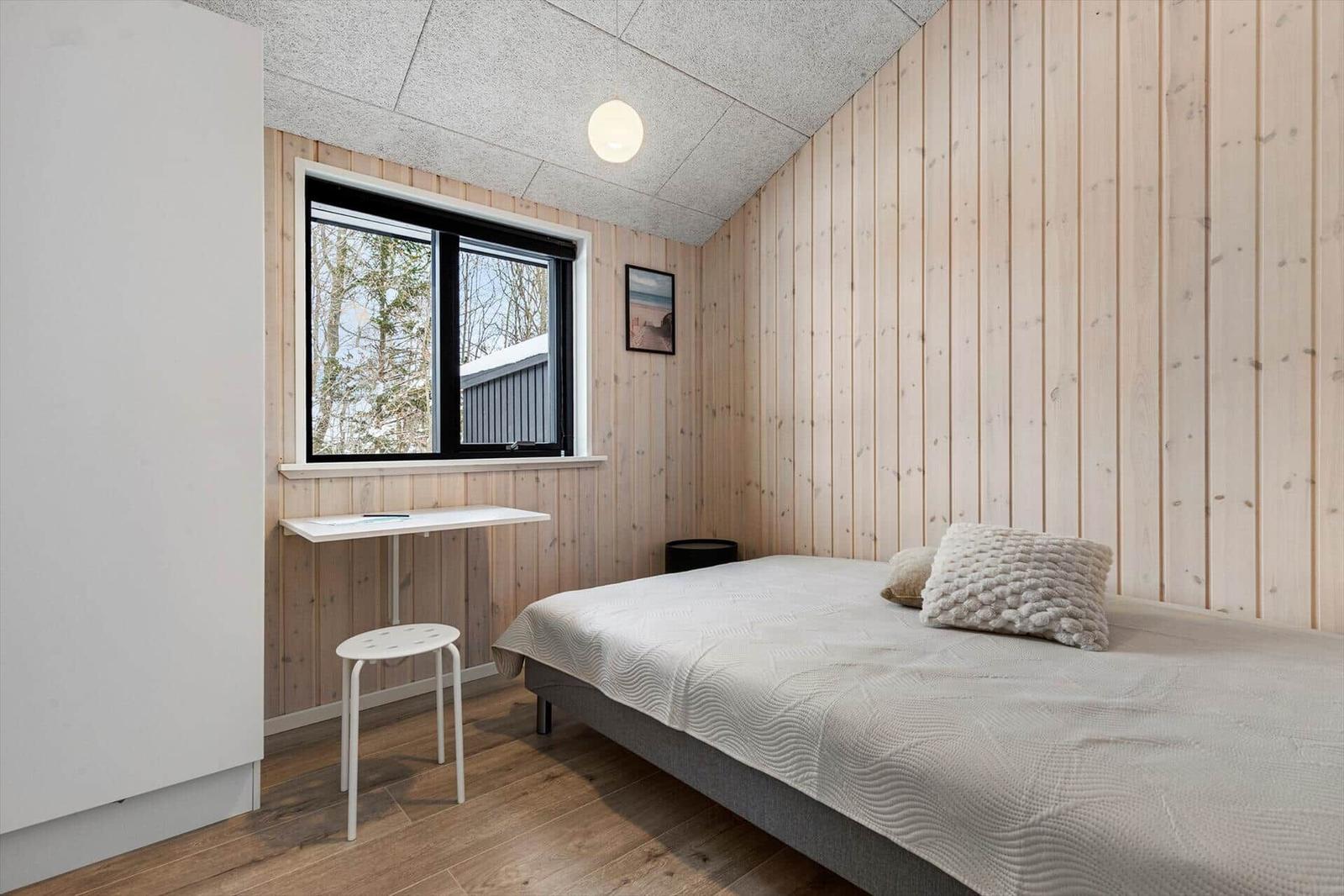 Schlafzimmer mit Bett, Schreibtisch und Fenster zur Aussicht.