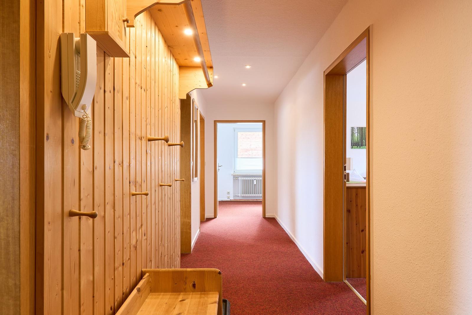 Flur mit Holzwand, rotem Teppich und Türen zu Räumen
