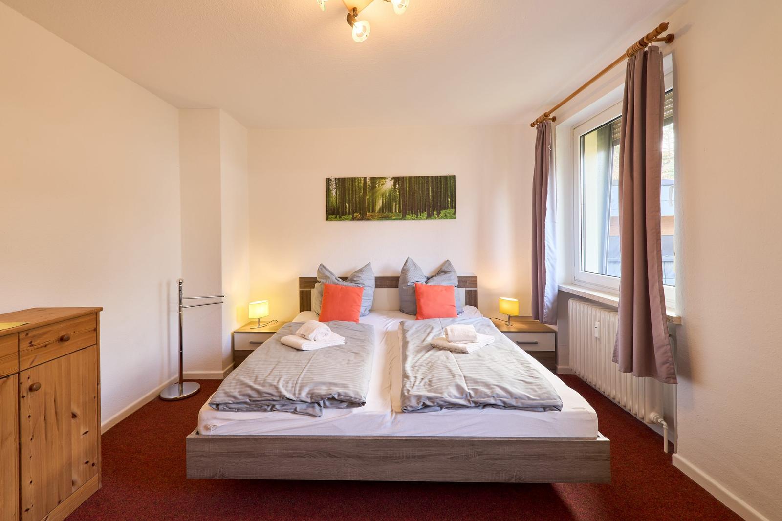 Schlafzimmer mit Doppelbett, Nachttischen und Fenster.