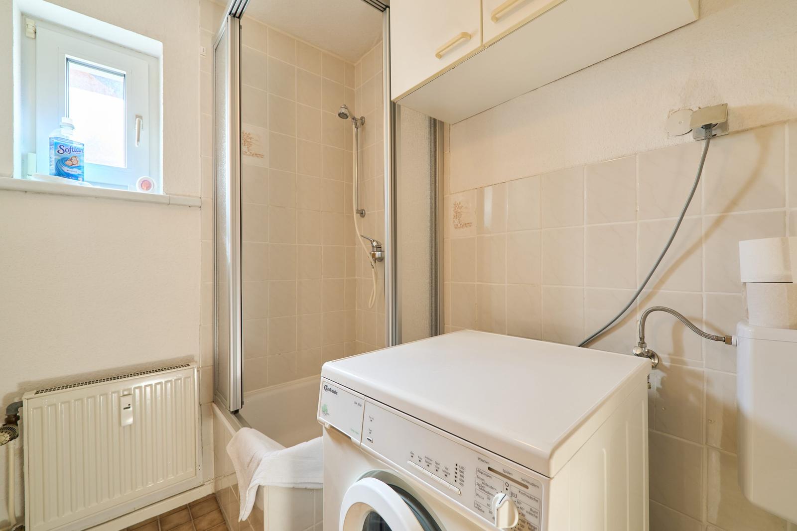 Badezimmer mit Dusche, Waschmaschine und Fenster