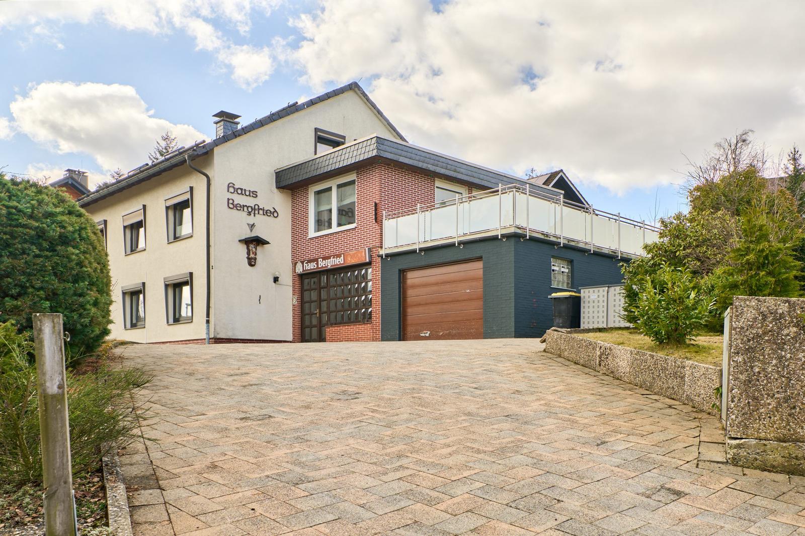 Haus Bergfried mit Garage und Balkon. Pflasterplatz vor dem Eingang.