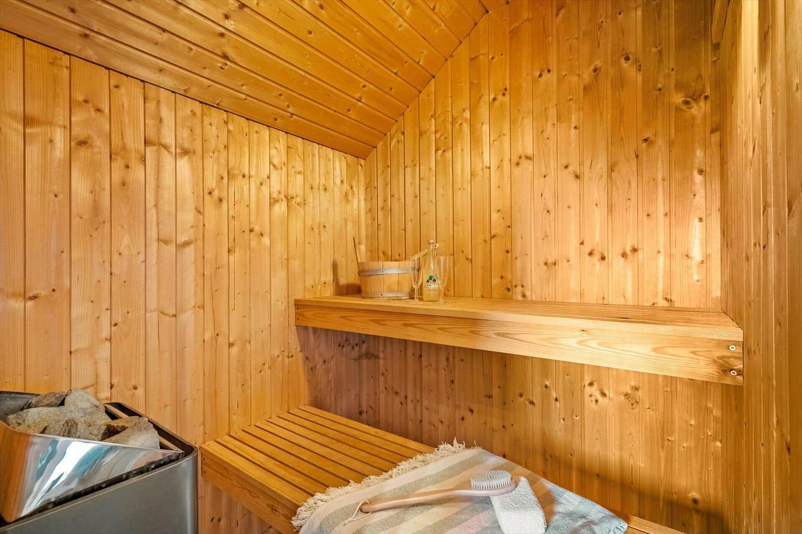 Sauna mit Holzwand, Sitzbank, Holzregal und Steinmulde.