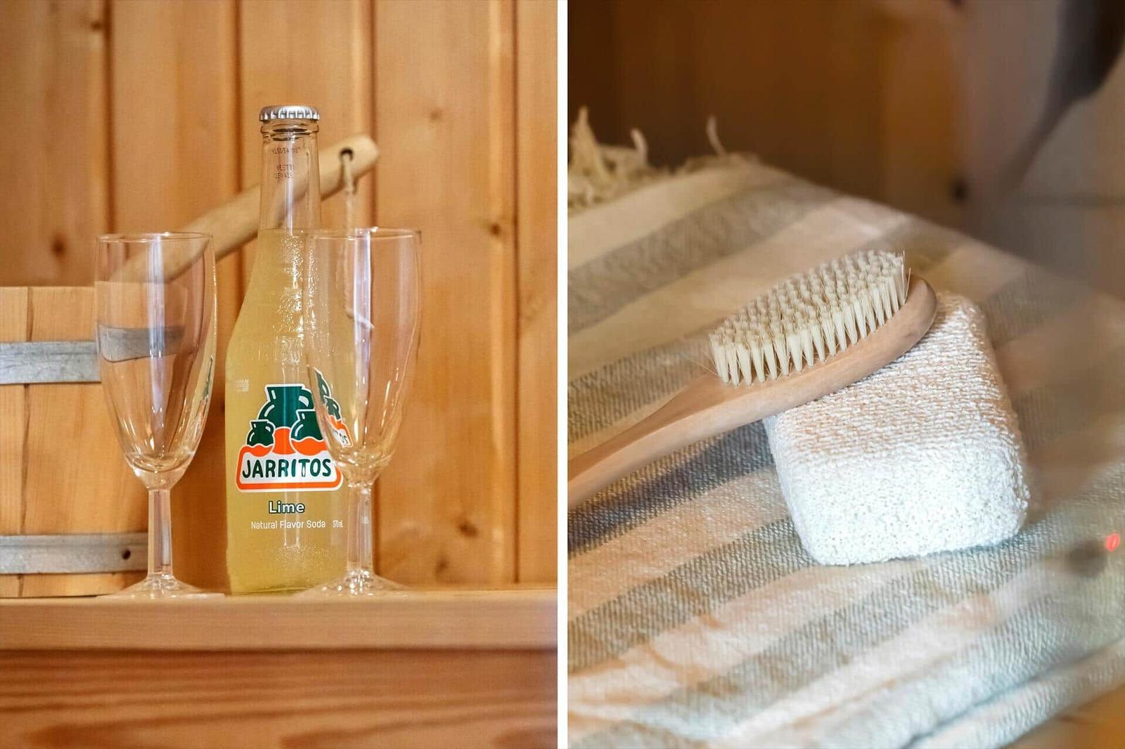 Ein Sauna mit Getränk und zwei Gläsern. Eine Bürste liegt auf einem Handtuch.