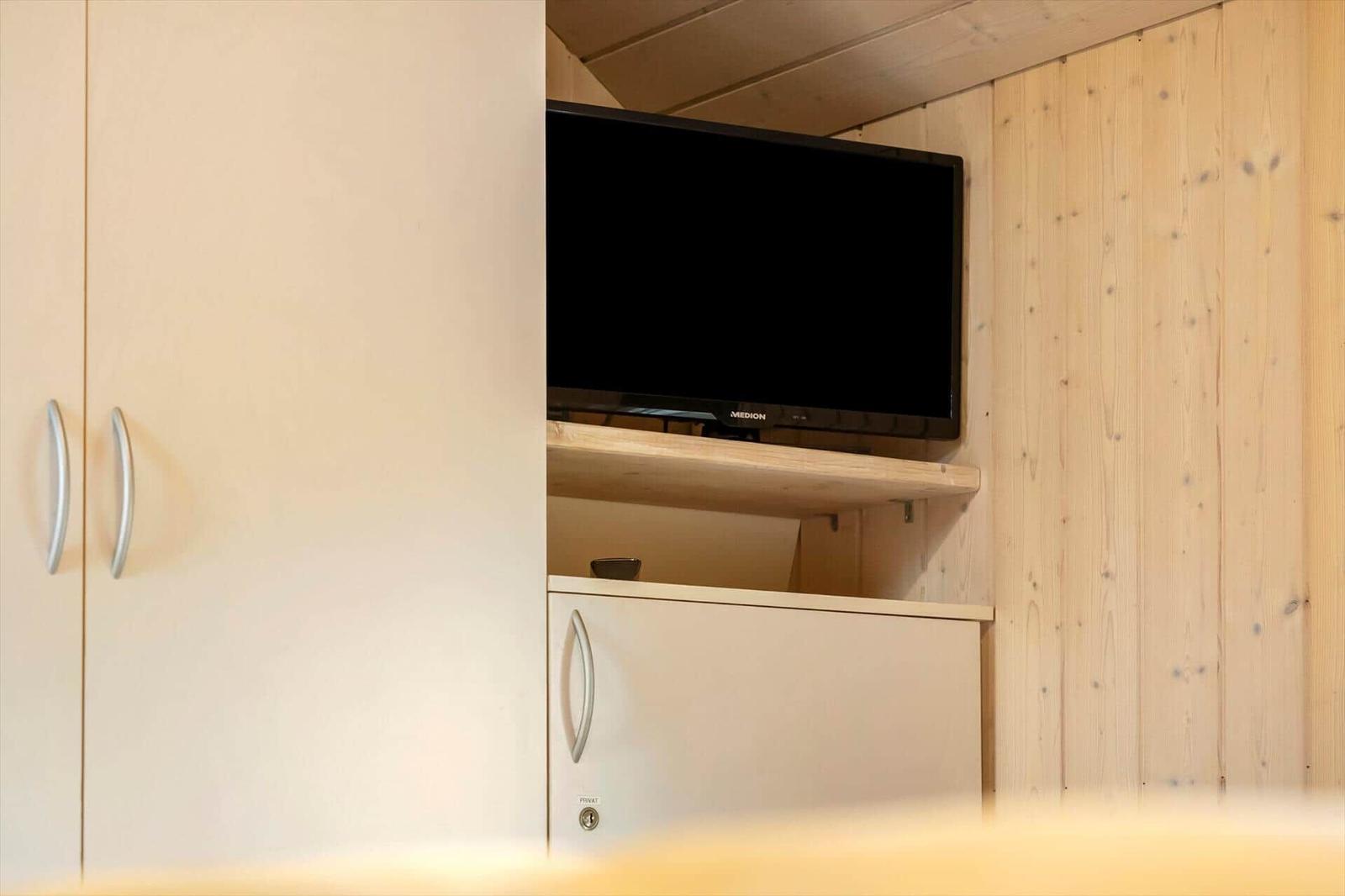 Fernseher in eingebauter Nische mit Holzwand und Schränken