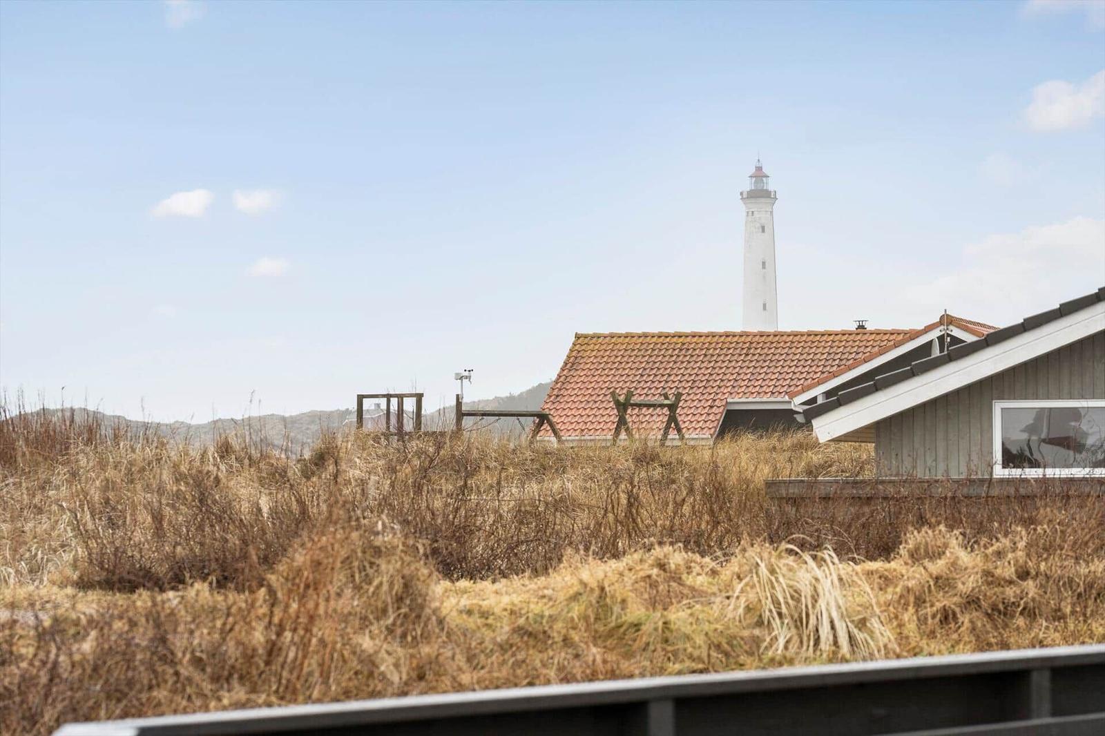 Haus mit rotem Dach und Leuchtturm im Hintergrund.
