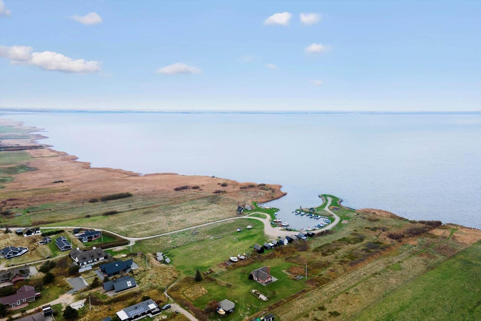 Aerial view of coastal village with houses, boats, and wide water.